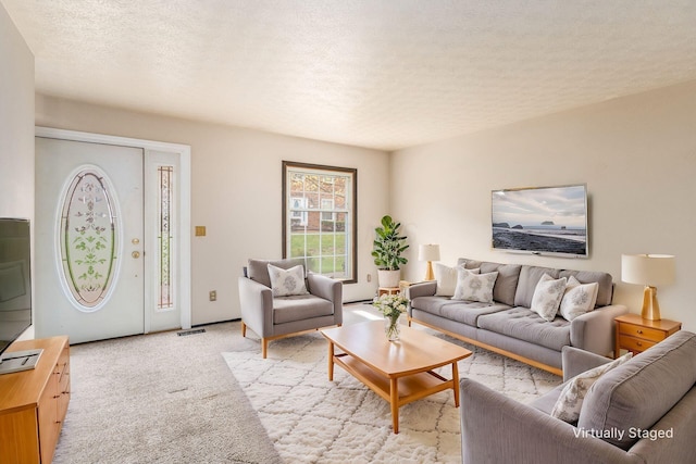 living area featuring light colored carpet, visible vents, and a textured ceiling