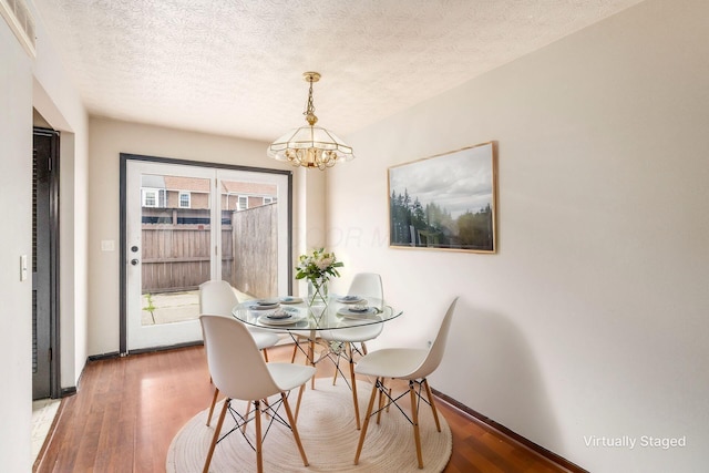 dining room with baseboards, a textured ceiling, wood finished floors, and an inviting chandelier