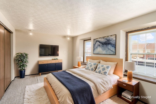 bedroom featuring light carpet, baseboards, and a textured ceiling