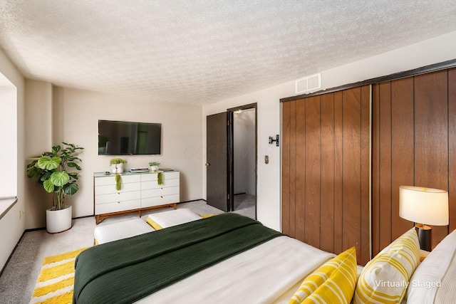 bedroom featuring light colored carpet, visible vents, and a textured ceiling