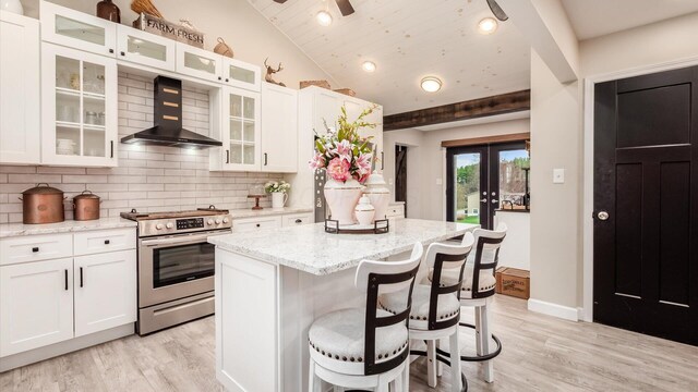 5456 Skyline Dr, Cambridge, OH 43725 - kitchen featuring decorative backsplash, white cabinets, wall chimney range hood, vaulted ceiling, and electric range