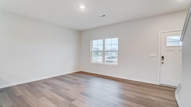 foyer entrance featuring baseboards, visible vents, and wood finished floors