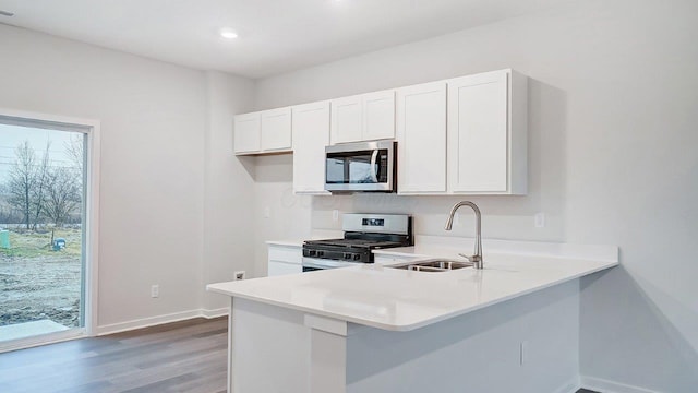 kitchen with light countertops, light wood-style flooring, appliances with stainless steel finishes, white cabinetry, and a sink