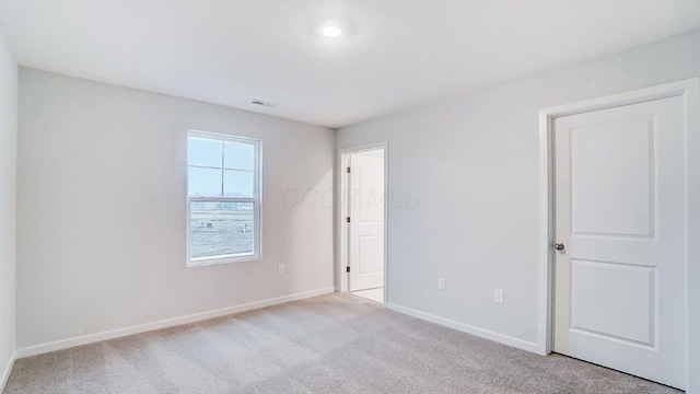 unfurnished room with light colored carpet, visible vents, and baseboards