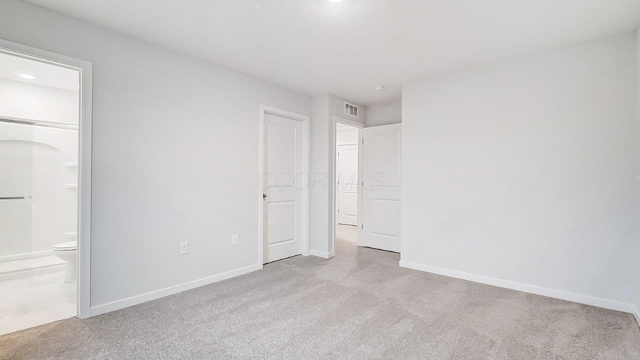 unfurnished bedroom featuring connected bathroom, baseboards, visible vents, and carpet floors