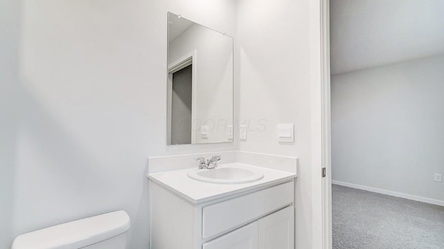 half bath featuring baseboards, toilet, and vanity
