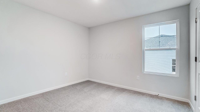 carpeted empty room featuring baseboards