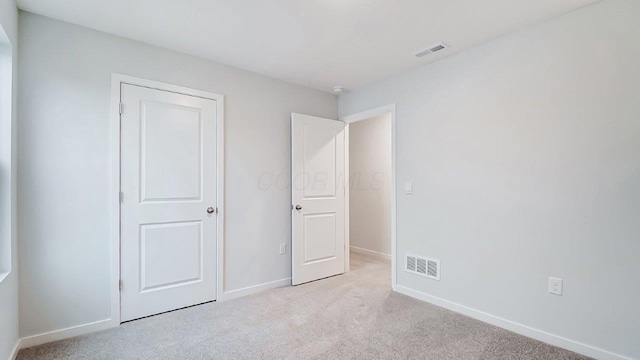 unfurnished bedroom with light carpet, baseboards, and visible vents