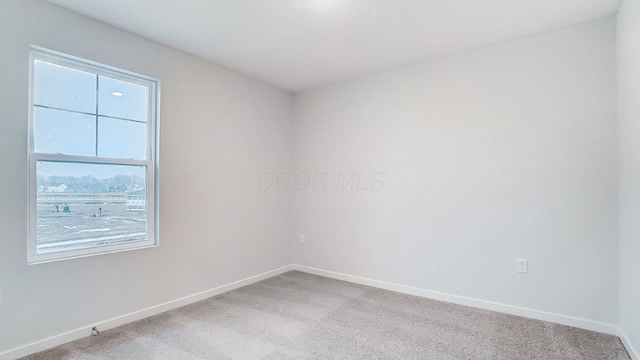 empty room with baseboards and light colored carpet