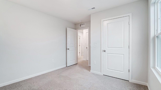 unfurnished bedroom featuring light carpet, baseboards, and visible vents