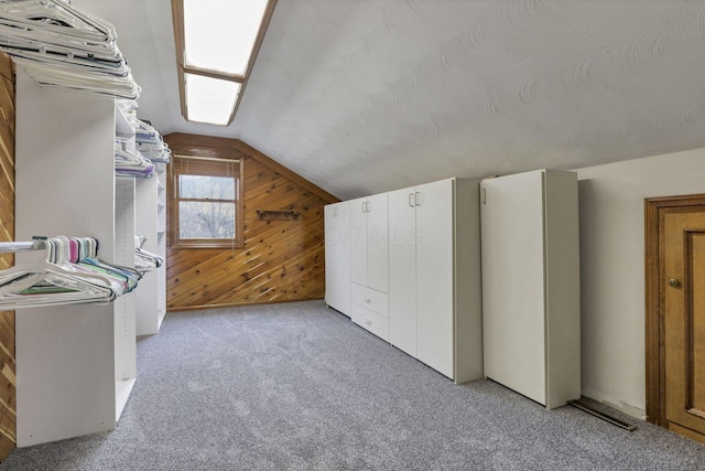 additional living space with light colored carpet, wood walls, and lofted ceiling