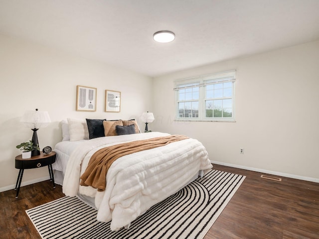 bedroom with baseboards, visible vents, and wood finished floors