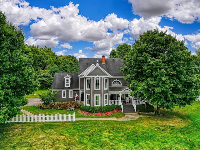 view of front of home featuring a front lawn, a chimney, covered porch, and fence