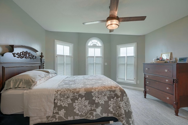 bedroom with light colored carpet, baseboards, and a ceiling fan
