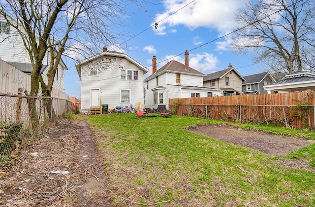 rear view of property featuring a yard, a fenced backyard, and entry steps