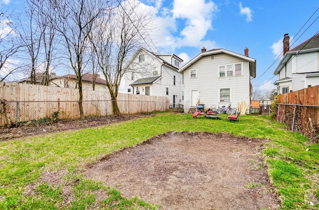 back of property featuring a yard, a fenced backyard, and a chimney