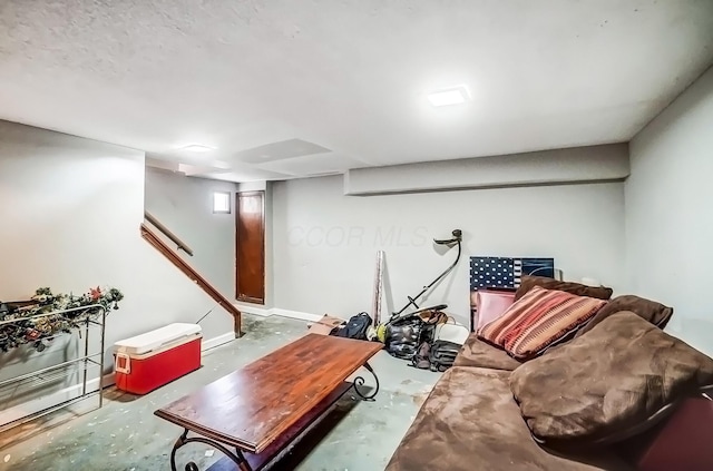 living room featuring baseboards, stairway, and unfinished concrete floors