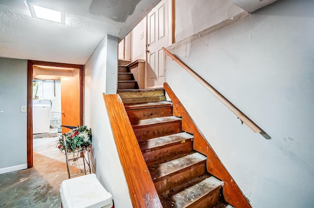 stairs featuring concrete flooring, washer / clothes dryer, and a textured ceiling