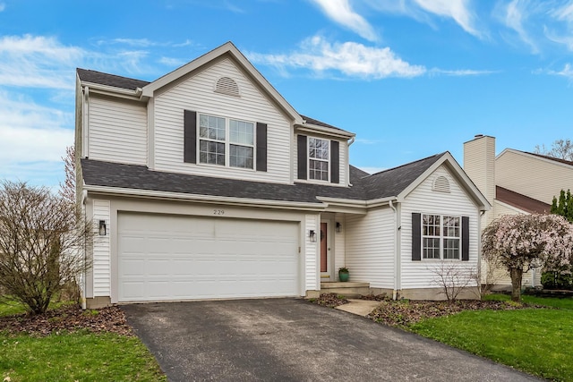 traditional home with a garage, driveway, and a shingled roof