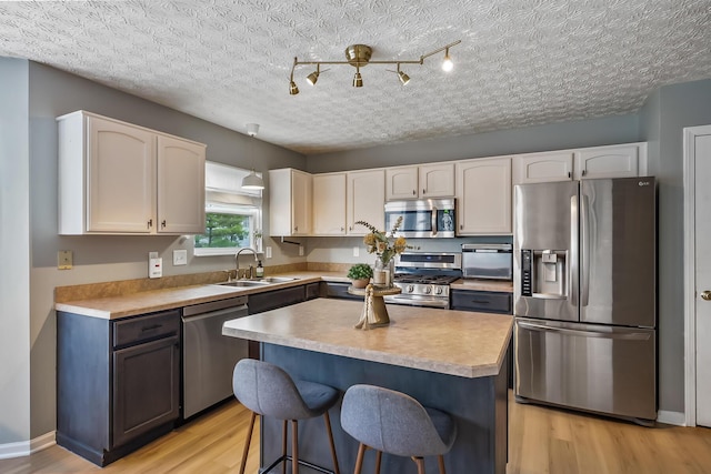 kitchen with stainless steel appliances, a breakfast bar area, light wood-type flooring, and a sink