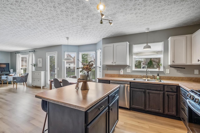 kitchen featuring white cabinets, light wood-type flooring, a sink, and appliances with stainless steel finishes