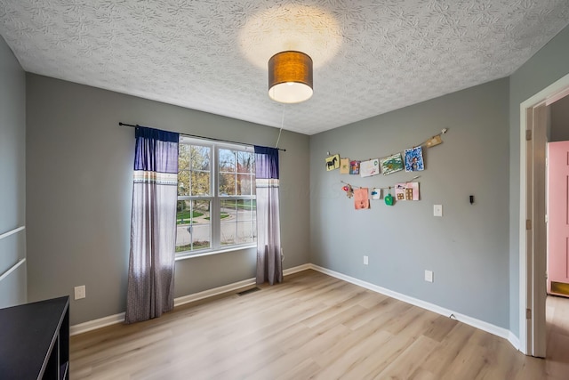 unfurnished bedroom with light wood finished floors, visible vents, baseboards, and a textured ceiling