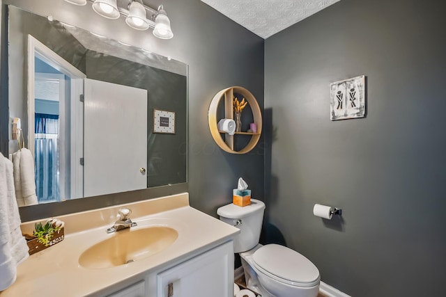 bathroom with toilet, a textured ceiling, vanity, and baseboards