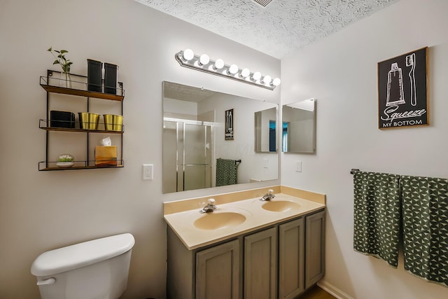 bathroom with a sink, toilet, a stall shower, and a textured ceiling
