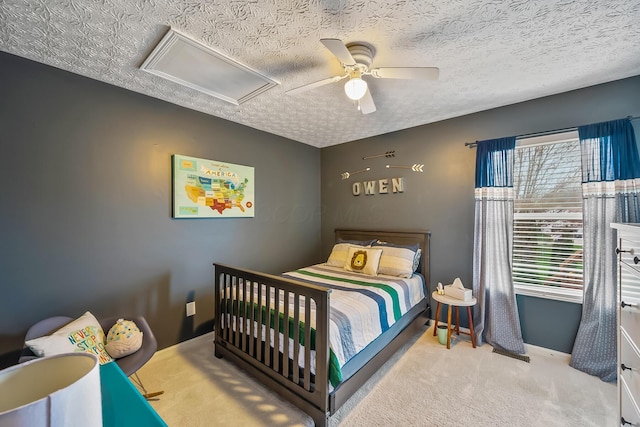 bedroom featuring baseboards, ceiling fan, carpet, a textured ceiling, and attic access
