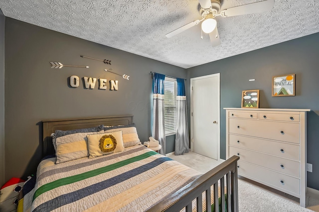 bedroom featuring light carpet, a textured ceiling, and a ceiling fan