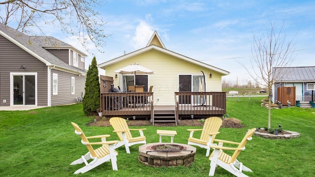 back of house with a fire pit, a wooden deck, and a yard