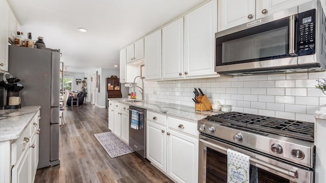 kitchen with a sink, white cabinetry, tasteful backsplash, dark wood-style floors, and stainless steel appliances