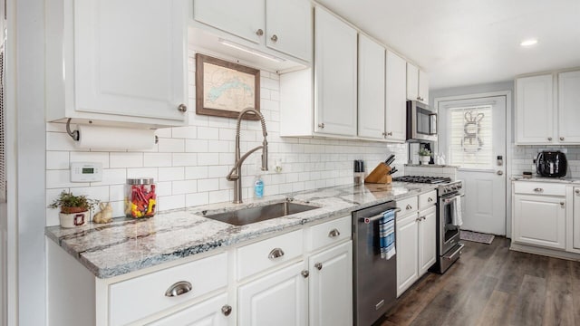 kitchen featuring a sink, backsplash, white cabinetry, appliances with stainless steel finishes, and dark wood finished floors