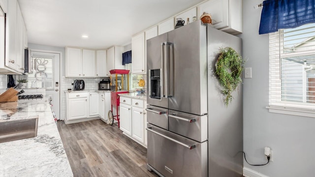 kitchen with white cabinetry, wood finished floors, tasteful backsplash, and high end refrigerator