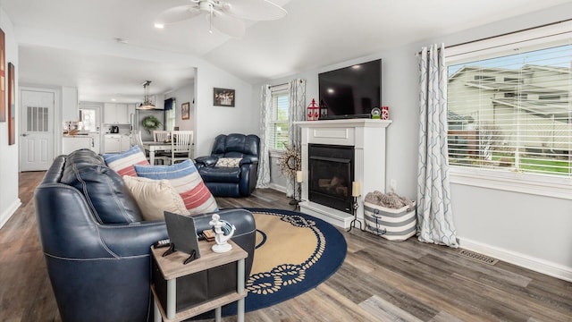living area with lofted ceiling, ceiling fan, visible vents, a fireplace, and wood finished floors