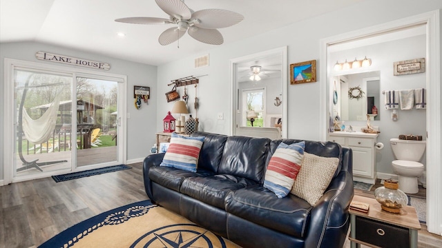 living area with vaulted ceiling, wood finished floors, baseboards, visible vents, and ceiling fan
