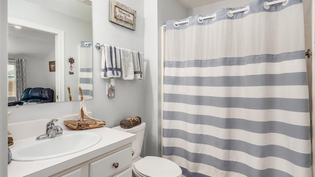 bathroom featuring toilet, vanity, and a shower with curtain