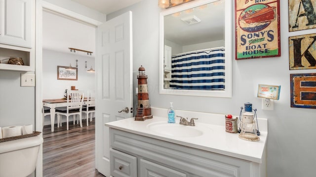 full bathroom with visible vents, a shower with shower curtain, toilet, wood finished floors, and vanity