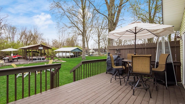 deck with outdoor dining area, a gazebo, fence, and a lawn