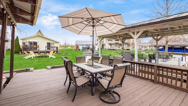 deck featuring a lawn, a fire pit, and outdoor dining space