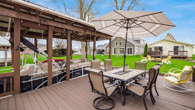dock area with a lawn, outdoor dining area, and a wooden deck