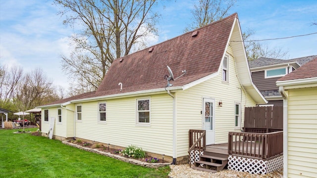 rear view of property featuring roof with shingles, a yard, and a wooden deck