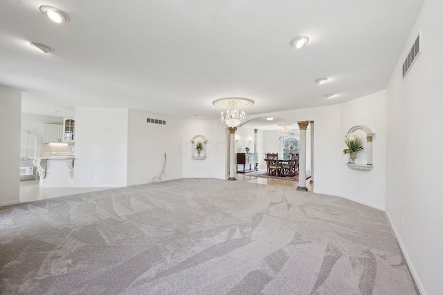unfurnished living room with visible vents, light colored carpet, arched walkways, and a notable chandelier