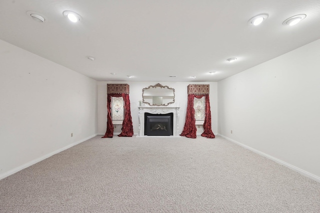 unfurnished living room with carpet flooring, a fireplace, and baseboards