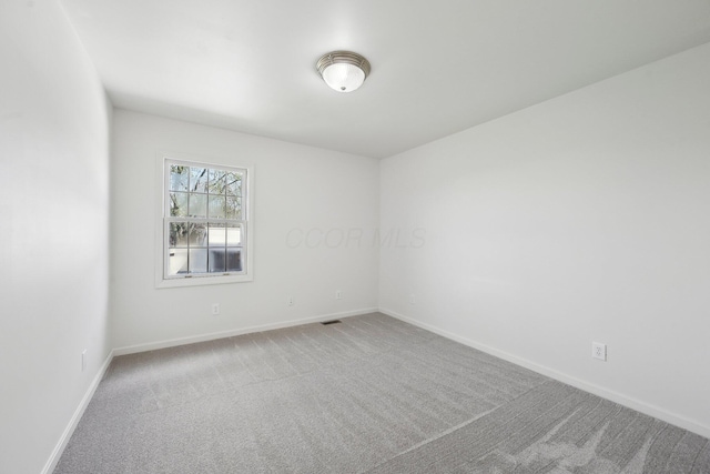 spare room featuring carpet flooring, baseboards, and visible vents