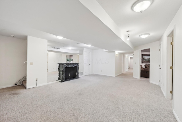 unfurnished living room featuring baseboards, stairway, light colored carpet, and a fireplace with flush hearth