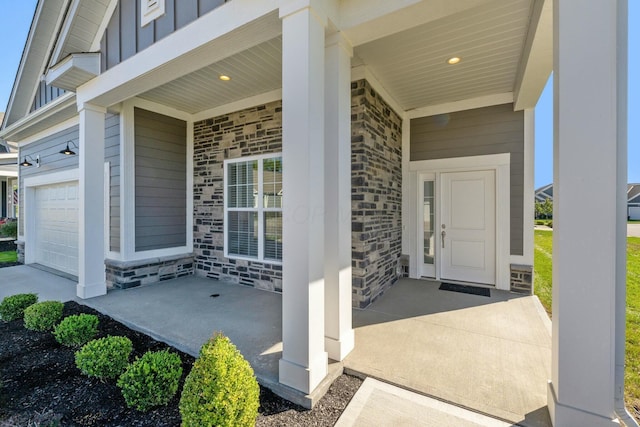 view of exterior entry with a porch, board and batten siding, stone siding, and an attached garage