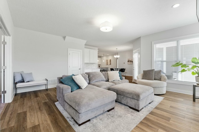 living area featuring recessed lighting, baseboards, an inviting chandelier, and wood finished floors