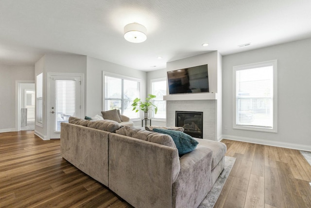 living room with visible vents, recessed lighting, wood finished floors, a brick fireplace, and baseboards