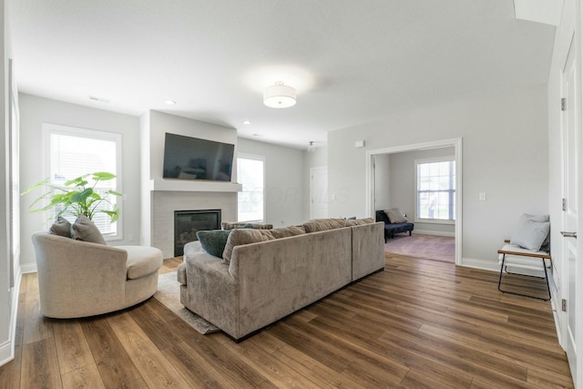 living area with visible vents, a fireplace, dark wood-style floors, and baseboards